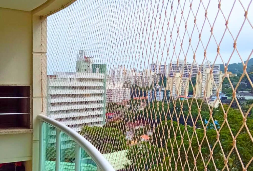 Redes de proteção instaladas em sacada de apartamento em Florianópolis com vista para o mar.
