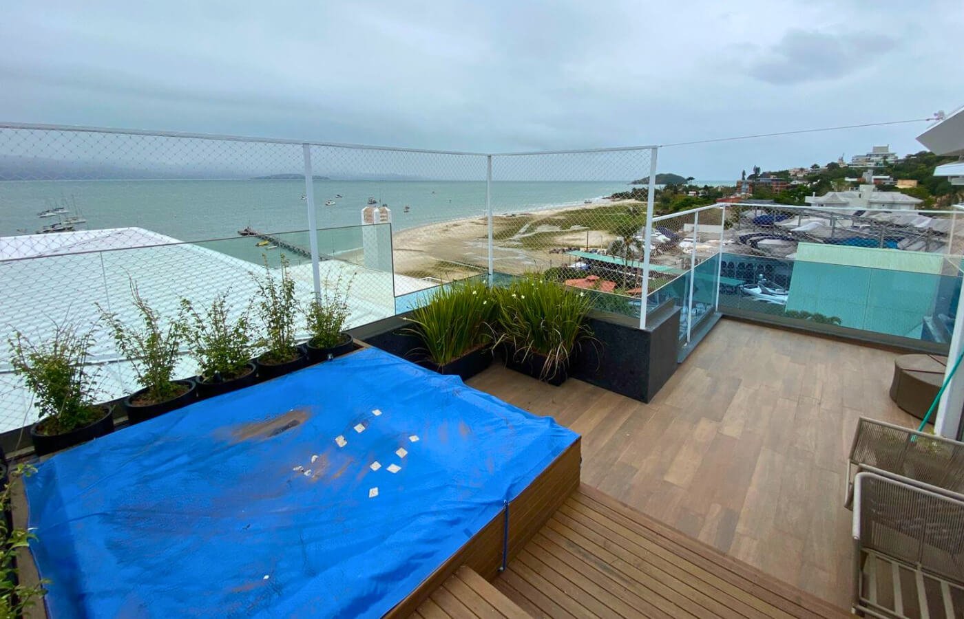 Área de lazer em cobertura (rooftop) com deck de madeira e piscina coberta por lona azul