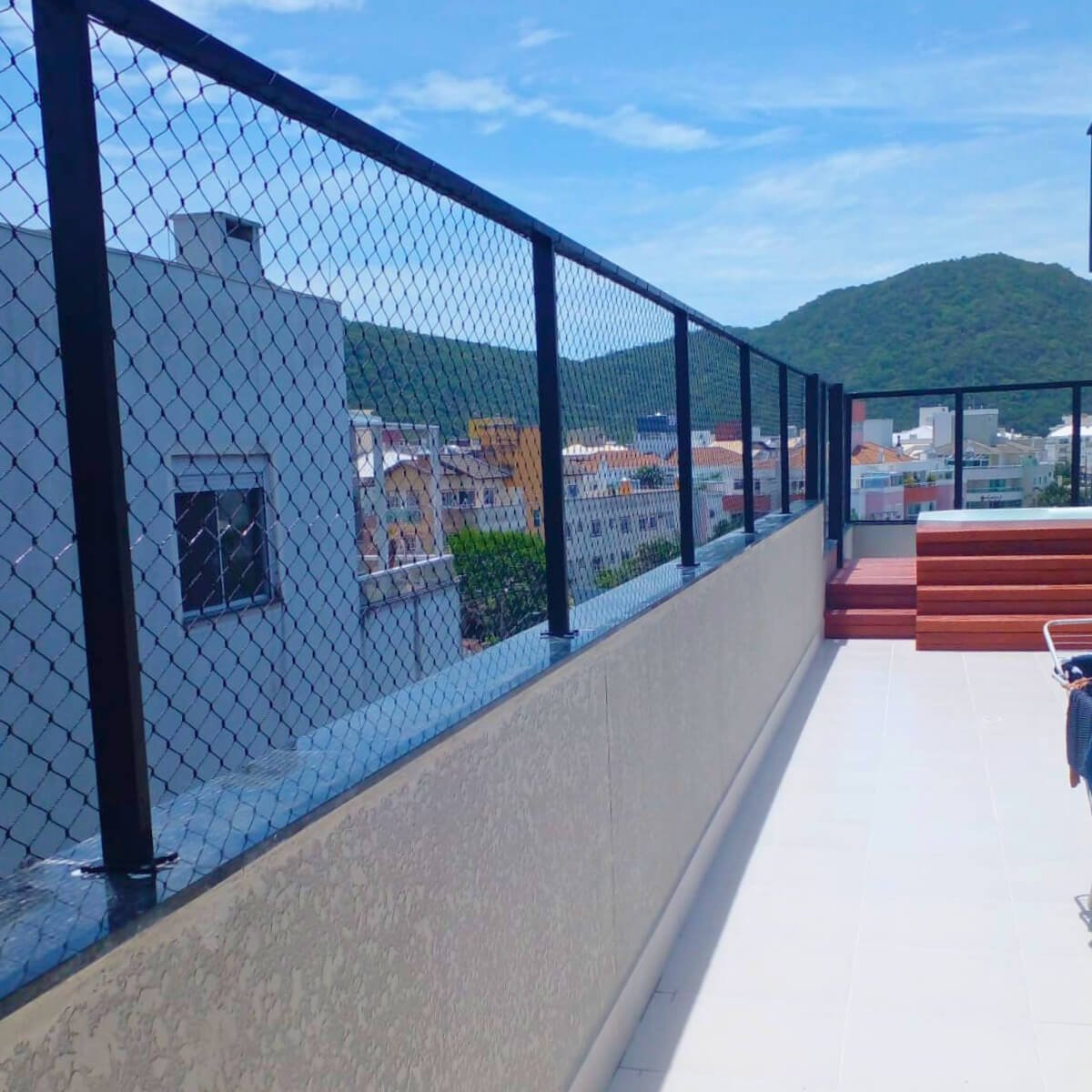 Sacada extensa com mureta e estrutura metálica preta adicionada para a fixação firme da rede de proteção.